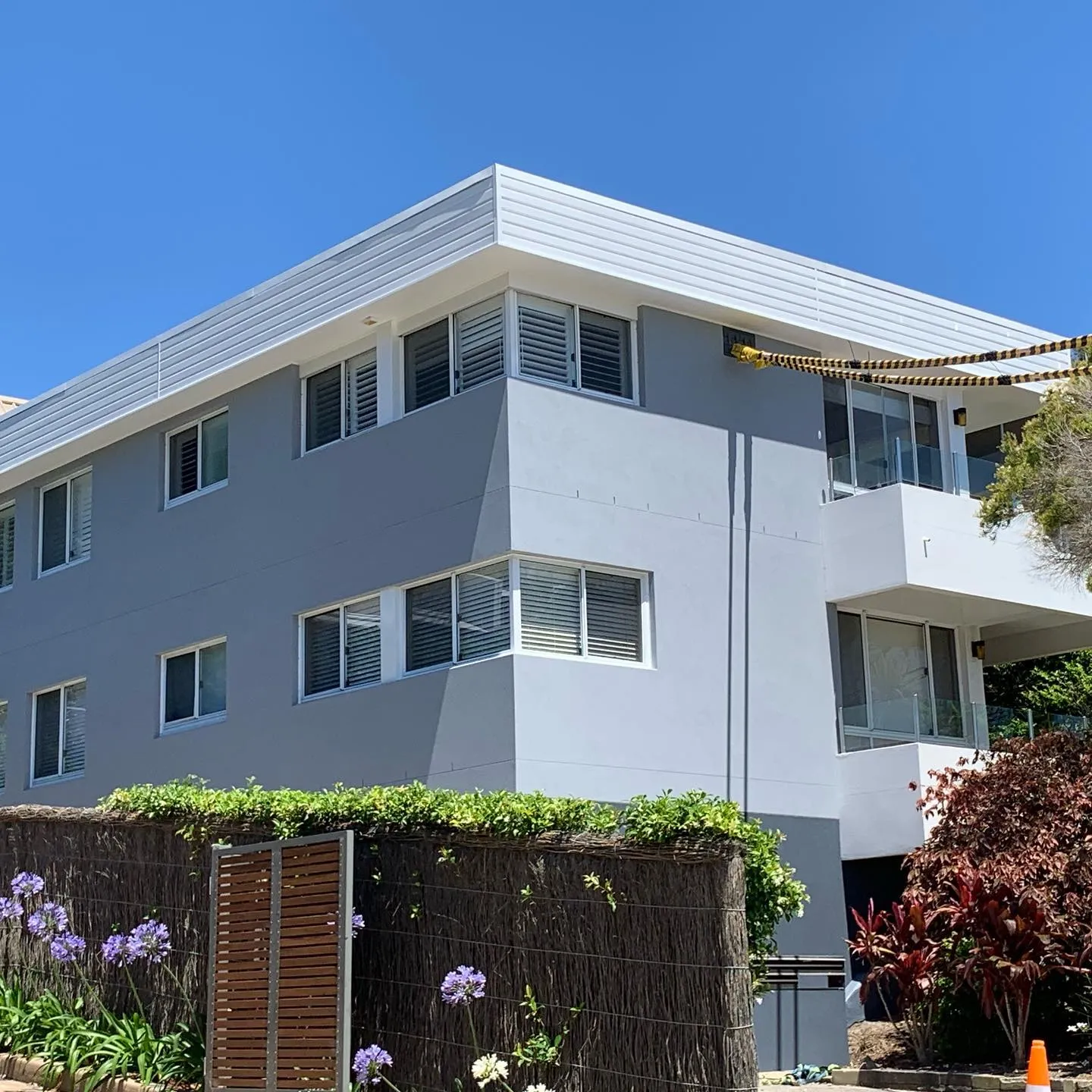Freshly rendered three-storey apartment block behind a garden