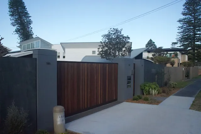 Charcoal rendered entry walls framing a timber driveway gate
