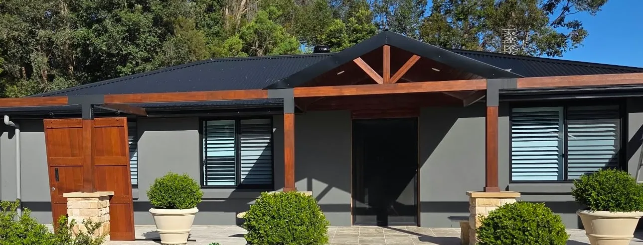 Grey rendered home with timber gable entry