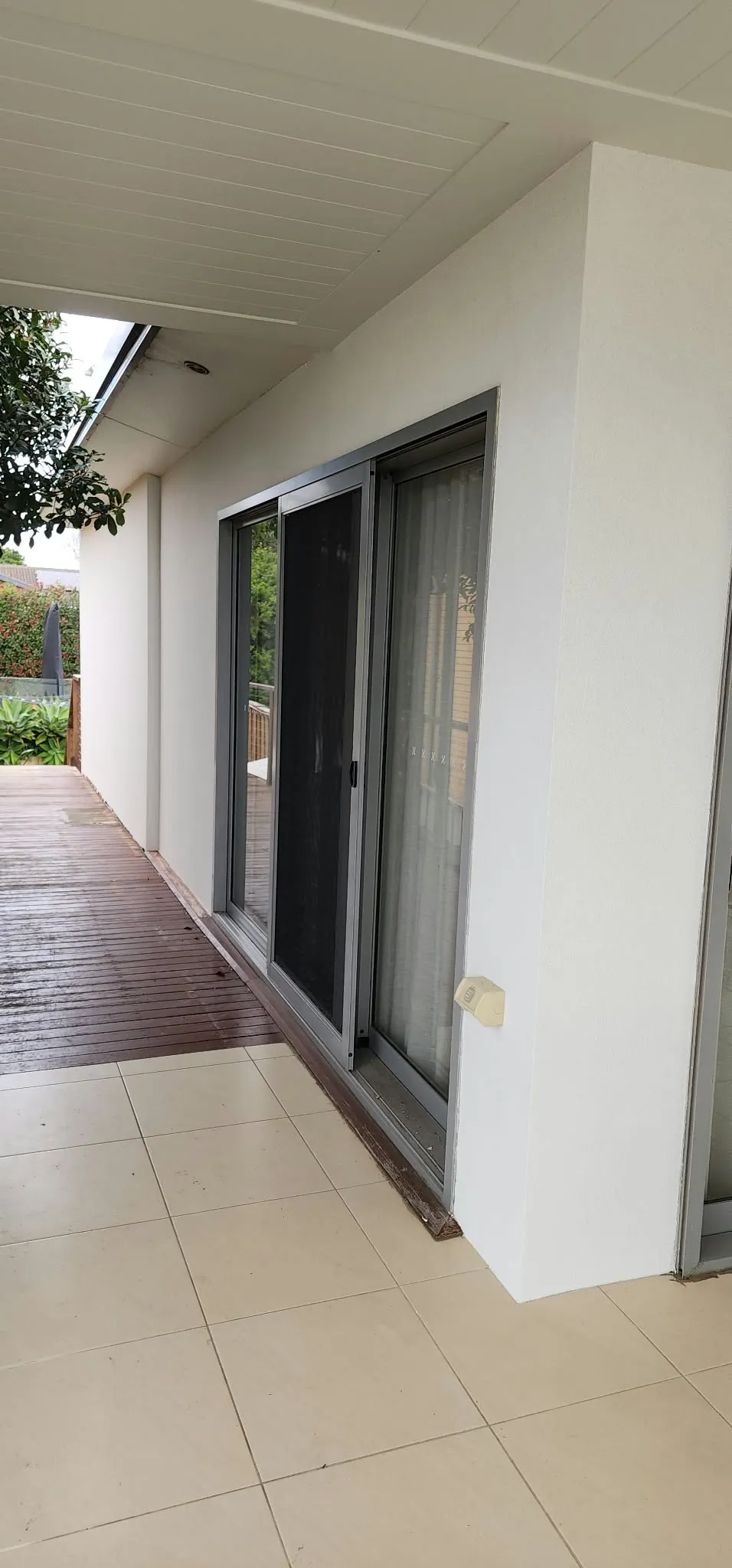 Smooth white render beside sliding doors on a tiled patio
