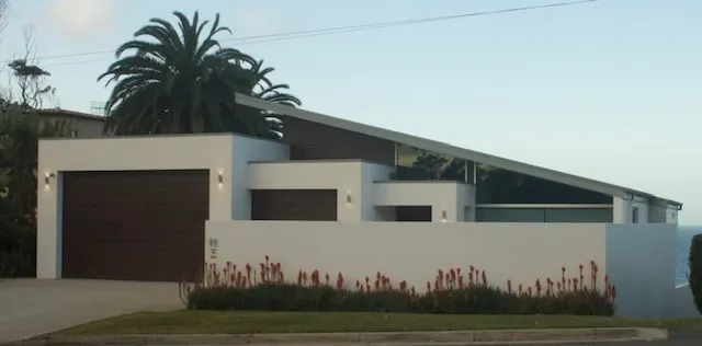 Wide view of a modern white rendered home with timber garage doors